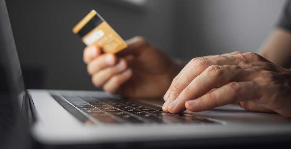 Man hand holding credit card and using laptop at home. Businessman or entrepreneur working in office. Online shopping, internet banking, store online, payment, spending money, e-commerce concept