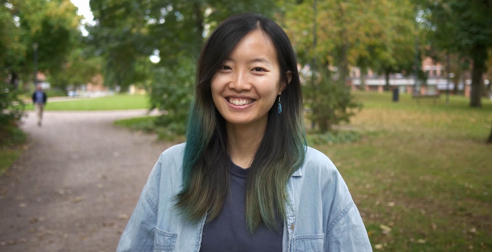 Wu Mingmin står utomhus i en parkmiljö